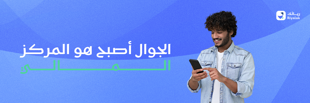 شاب سعودي بلباس عصري تيشيرت وقميص جينز، ممسك بجواله الآيفون في يده ويطلع عليه مبتسما ومتحمساً لما يراه في الجوال.